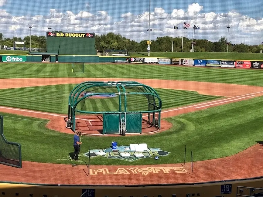 A baseball field with a green tarp on the ground.