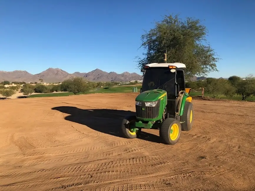 A tractor is parked in the dirt near some trees.